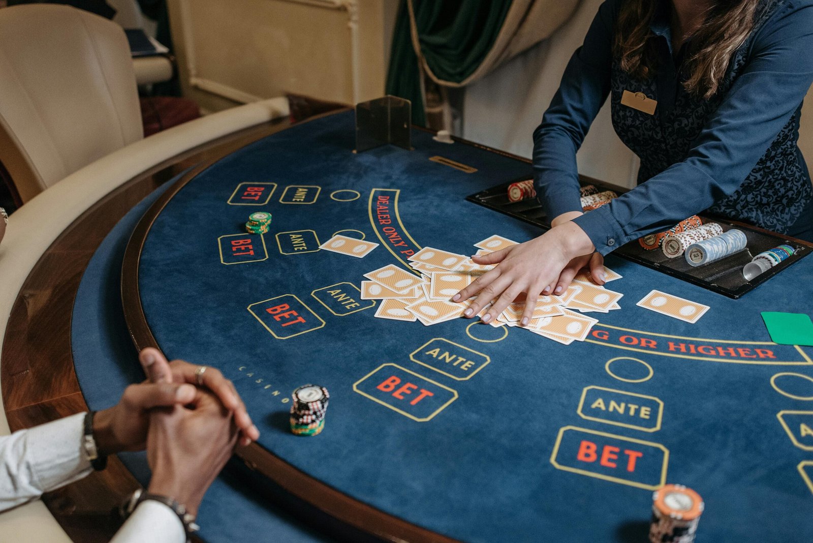 Close-up of a casino dealer shuffling cards on a gambling table with chips and bet labels.